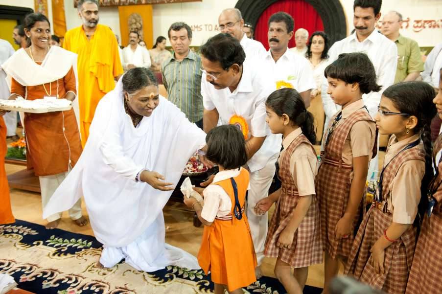 Amma handing kerchiefs to schoolchildren